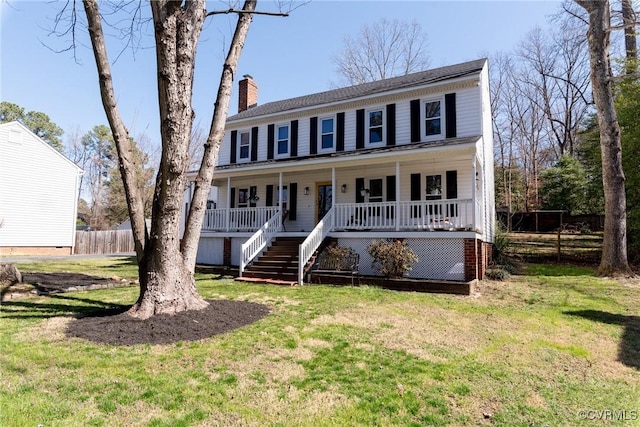 colonial-style house with a front lawn, covered porch, and a chimney