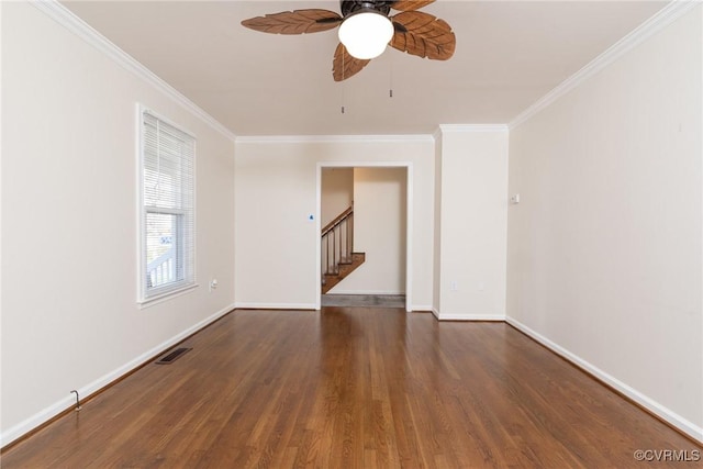 empty room featuring crown molding, wood finished floors, visible vents, and baseboards