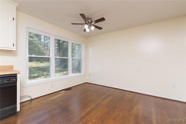 unfurnished room with a ceiling fan, visible vents, dark wood-style flooring, and baseboards