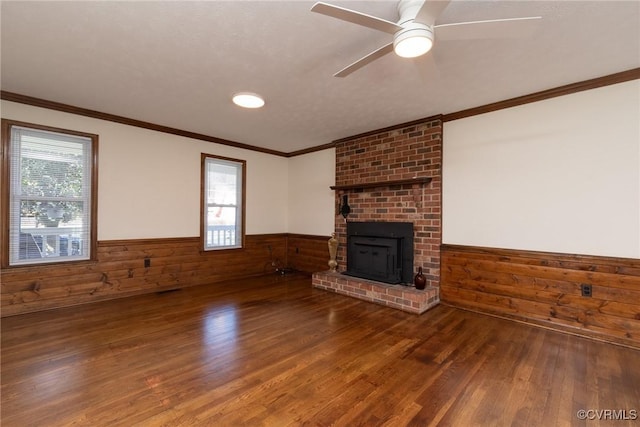 unfurnished living room featuring wooden walls, ornamental molding, wood finished floors, and wainscoting