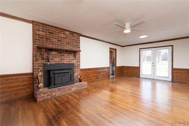 unfurnished living room with wainscoting, french doors, a textured ceiling, and wood finished floors