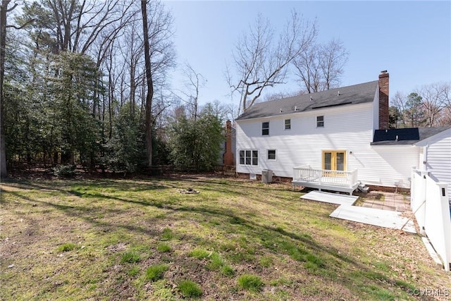 rear view of house featuring a deck, fence, a yard, cooling unit, and a chimney