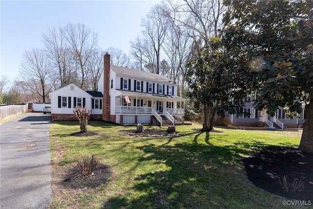 view of front of property featuring crawl space, covered porch, a chimney, and a front lawn