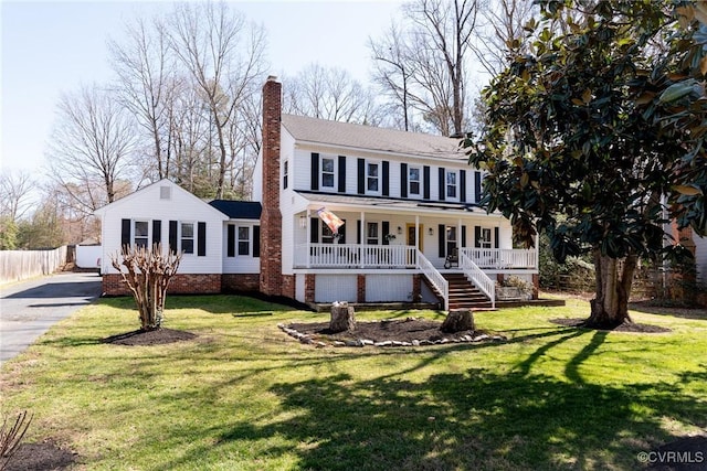 view of front facade featuring driveway, fence, covered porch, a front yard, and a chimney