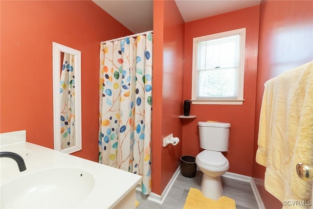 bathroom with vanity, wood finished floors, baseboards, curtained shower, and toilet