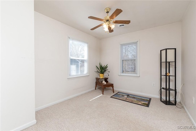 living area featuring visible vents, baseboards, carpet, and a ceiling fan