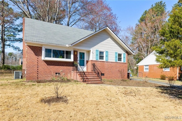 view of front of property with brick siding, a front yard, roof with shingles, cooling unit, and crawl space