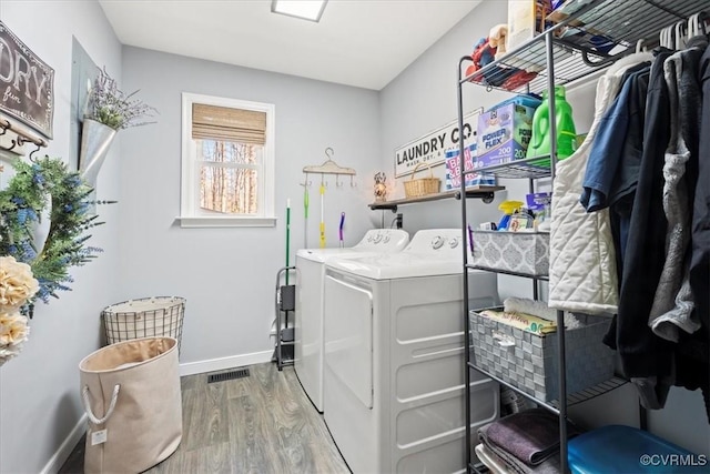 clothes washing area with visible vents, baseboards, laundry area, wood finished floors, and independent washer and dryer