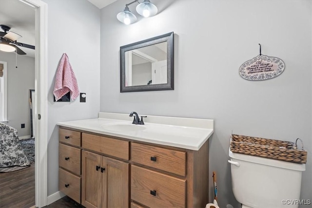 bathroom with baseboards, ceiling fan, toilet, wood finished floors, and vanity