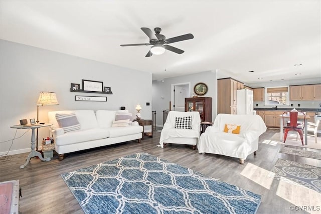 living area featuring wood finished floors, baseboards, and ceiling fan