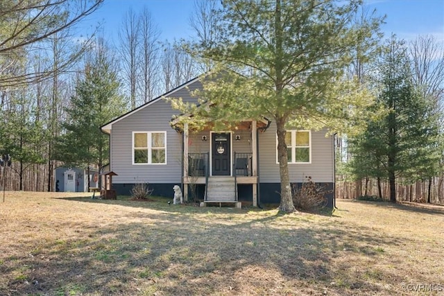 view of front facade with a front yard, an outbuilding, covered porch, and crawl space