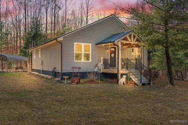 back of property at dusk featuring a carport, a lawn, and metal roof