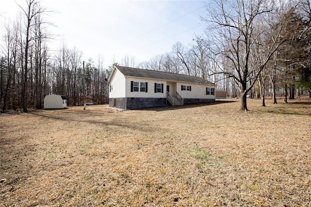 ranch-style home featuring an outbuilding, a storage unit, a front lawn, and crawl space