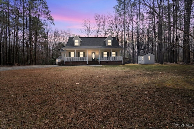 view of front of property with a porch, a front yard, a storage shed, crawl space, and an outbuilding