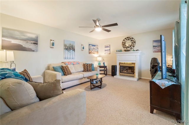 living area with baseboards, light colored carpet, a glass covered fireplace, and a ceiling fan