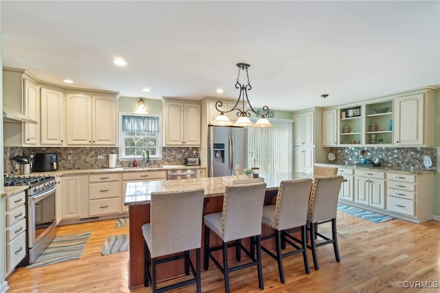 kitchen featuring a center island, light stone countertops, light wood-type flooring, appliances with stainless steel finishes, and a sink