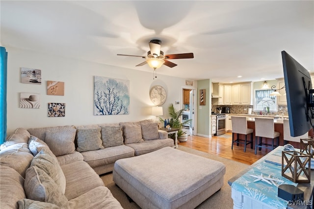 living area featuring light wood-style floors and ceiling fan