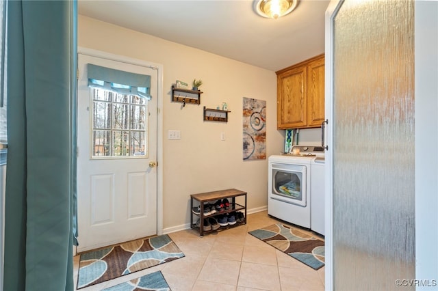 laundry room featuring washer and dryer, baseboards, cabinet space, and light tile patterned flooring