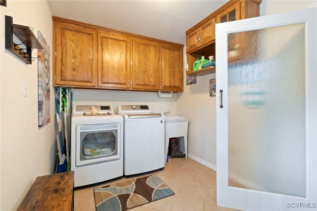 washroom with washing machine and clothes dryer, cabinet space, and light tile patterned flooring