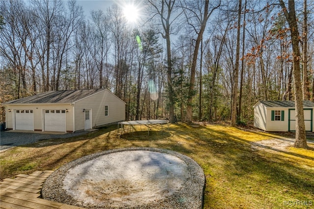 view of yard with an outdoor structure, a trampoline, and a garage