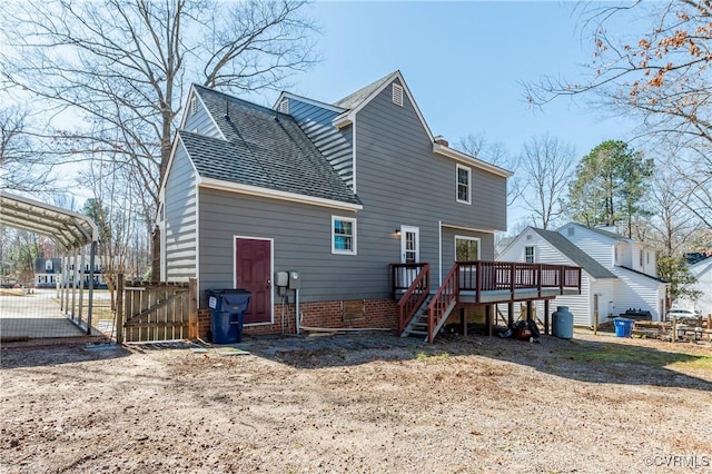 back of house featuring stairway, a wooden deck, roof with shingles, a carport, and a gate