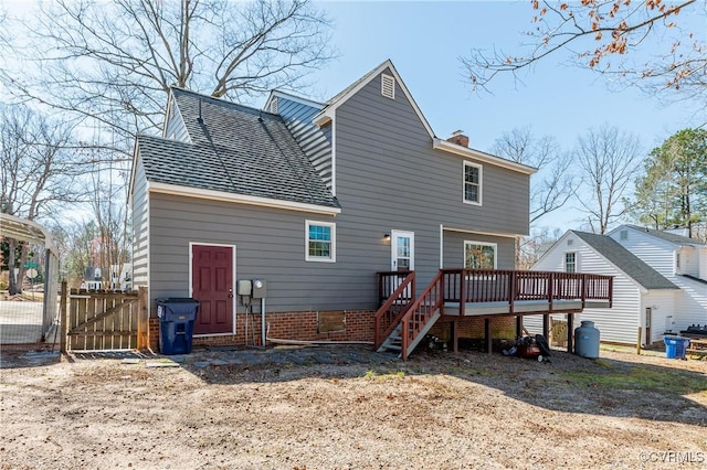 rear view of house with a gate, fence, a chimney, stairs, and a deck