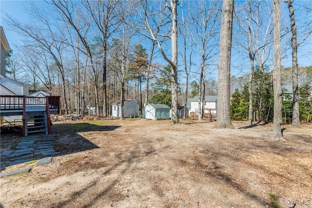 view of yard featuring an outdoor structure, a deck, stairs, and a shed