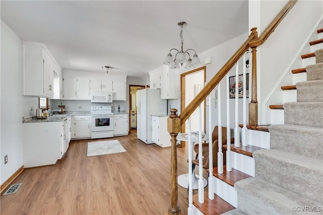 kitchen featuring white appliances, visible vents, light wood-style flooring, white cabinetry, and a notable chandelier