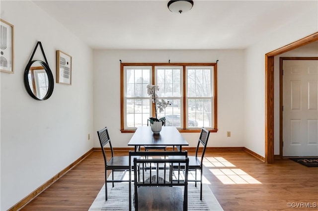 dining space with baseboards and wood finished floors