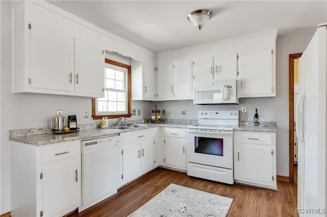 kitchen featuring wood finished floors, white appliances, white cabinetry, and a sink