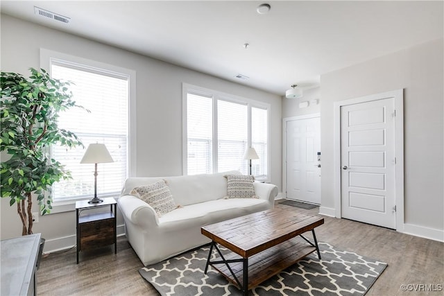 living room with visible vents, baseboards, and light wood-style floors