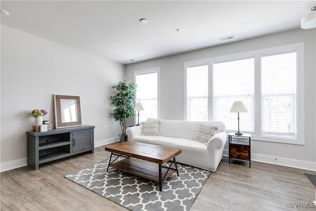 living area featuring wood finished floors, visible vents, and baseboards