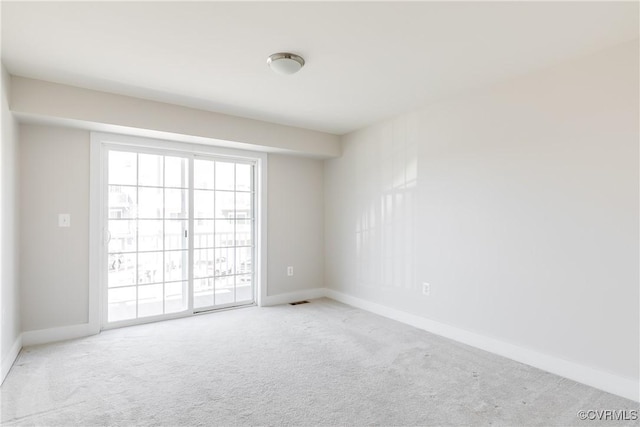 spare room featuring carpet flooring, visible vents, and baseboards