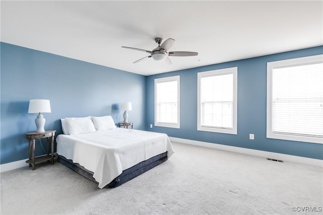 carpeted bedroom with a ceiling fan, baseboards, and visible vents