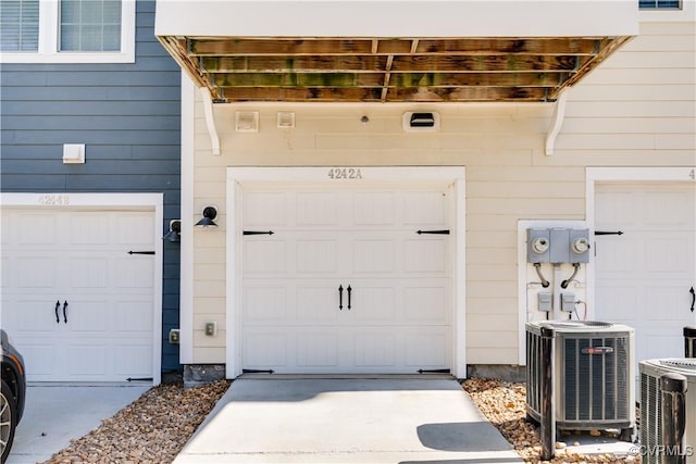 entrance to property featuring cooling unit, a garage, and driveway