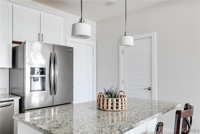 kitchen with white cabinetry, light stone countertops, appliances with stainless steel finishes, and a kitchen island