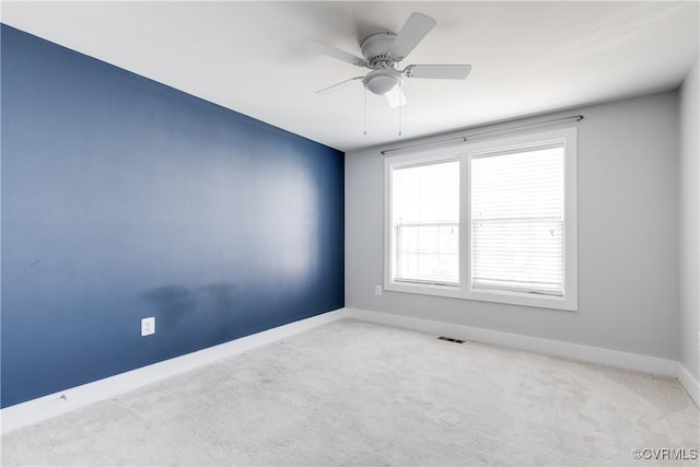 carpeted spare room featuring visible vents, baseboards, and ceiling fan