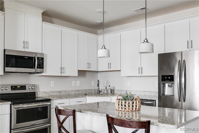 kitchen with visible vents, a sink, white cabinetry, stainless steel appliances, and a breakfast bar area