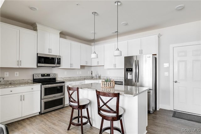 kitchen featuring a sink, white cabinets, wood finished floors, and stainless steel appliances