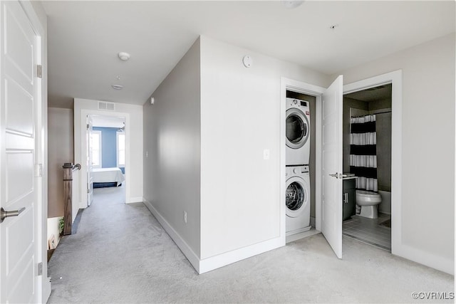 clothes washing area featuring laundry area, baseboards, stacked washer / drying machine, and visible vents