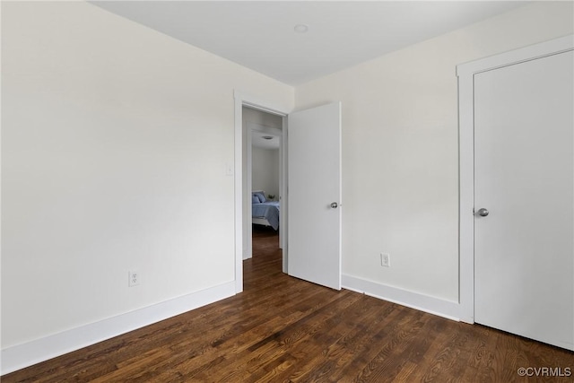 unfurnished bedroom featuring dark wood finished floors and baseboards