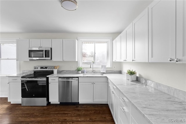 kitchen with appliances with stainless steel finishes, white cabinetry, and a sink