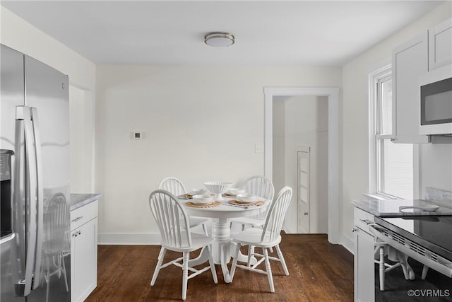 dining area featuring a wealth of natural light, baseboards, and dark wood finished floors