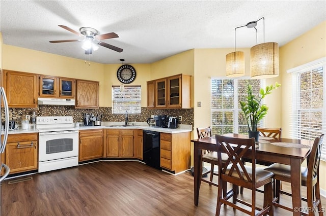 kitchen with under cabinet range hood, black dishwasher, brown cabinetry, white electric stove, and a sink