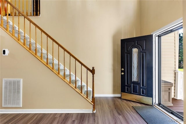 entrance foyer featuring stairway, wood finished floors, visible vents, baseboards, and a high ceiling