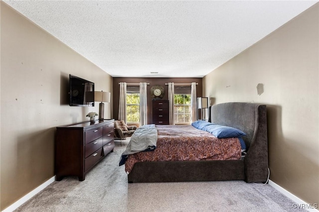 bedroom featuring light colored carpet, baseboards, and a textured ceiling