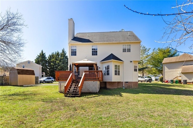 rear view of property featuring a deck, an outdoor structure, a lawn, and a chimney