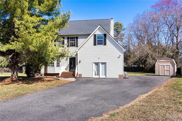 view of front of house featuring a shed, a chimney, and an outdoor structure