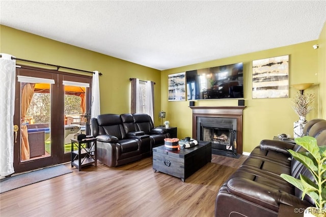 living area with a textured ceiling, wood finished floors, and a fireplace