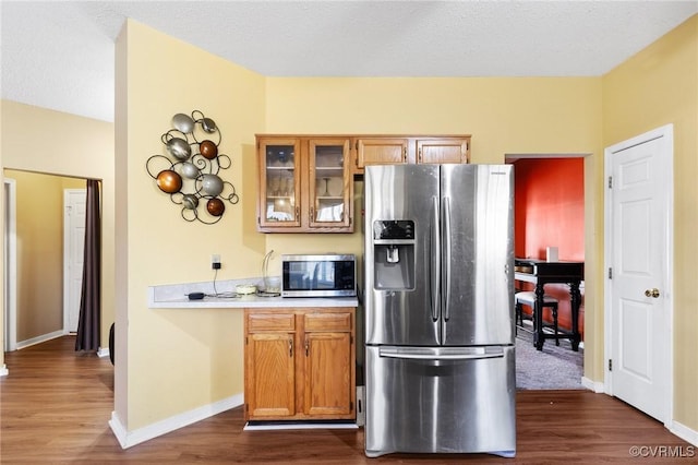 kitchen with glass insert cabinets, baseboards, dark wood finished floors, light countertops, and stainless steel appliances